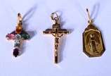 Três pendentes de ouro 18 k., sendo: 2 crucifix... - Três pendentes de ouro 18 k., sendo: 2 crucifixos sendo um deles com pedra colorida e medalha. (Por motivos de segurança a peça não se encontra ...