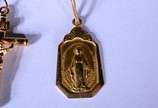 Três pendentes de ouro 18 k., sendo: 2 crucifix... - Três pendentes de ouro 18 k., sendo: 2 crucifixos sendo um deles com pedra colorida e medalha. (Por motivos de segurança a peça não se encontra ...
