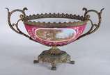 Fruteira de porcelana francesa com paisagem e c... - Fruteira de porcelana francesa com paisagem e cena romântica em policromia, sobre fundo rosa. Guarnição de metal dourado.