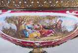 Fruteira de porcelana francesa com paisagem e c... - Fruteira de porcelana francesa com paisagem e cena romântica em policromia, sobre fundo rosa. Guarnição de metal dourado.