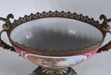 Fruteira de porcelana francesa com paisagem e c... - Fruteira de porcelana francesa com paisagem e cena romântica em policromia, sobre fundo rosa. Guarnição de metal dourado.