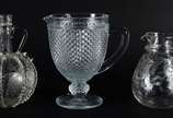 Três peças, sendo: 2 jarras para água, uma bico... - Três peças, sendo: 2 jarras para água, uma bico de jaca e outra com flores lavradas; e garrafa de cristal com alças decorada com moinho e cachos...