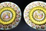 Par de medalhões de porcelana "Dom Pedro" decor... - Par de medalhões de porcelana "Dom Pedro" decorados com cenas românticas em policromia sobre fundo amarelo e guirlandas douradas.