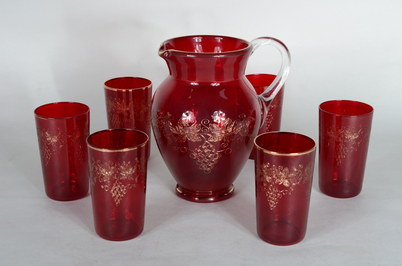 Conjunto com jarra e 6 copos de vidro vermelho decorados com cachos... - foto 1 de 9