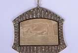 Pendente de madrepérola com figura de "biga" ro... - Pendente de madrepérola com figura de "biga" romana,  moldura de platina e ouro 18 k. cravejado com brilhantes.  (Por motivos de segurança a peç...