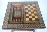 Mesa de jogo marroquina de madeira com incrusta... - Mesa de jogo marroquina de madeira com incrustações, tampo dobrável com tabuleiros para gamão, damas/xadrez e cartas. Desgastes.