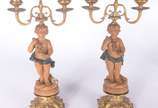 Quatro peças decorativas: sendo um par de cande... - Quatro peças decorativas: sendo um par de candelabros de metal dourado com figuras de "pucci" (um colado); e, par de colunas com figuras mitológ...