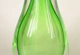 Três peças decorativas de vidro, sendo: vaso ve... - Três peças decorativas de vidro, sendo: vaso verde; centro de mesa laranja com bolhas internas; vaso feitio "lenço" com listras sobre fundo branco.