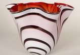 Três peças decorativas de vidro, sendo: vaso ve... - Três peças decorativas de vidro, sendo: vaso verde; centro de mesa laranja com bolhas internas; vaso feitio "lenço" com listras sobre fundo branco.