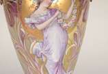 Ânfora Art Nouveau de porcelana europeia decora... - Ânfora Art Nouveau de porcelana europeia decorada com figura feminina e guirlandas florais em policromia e realces dourados, guarnição de bronze.