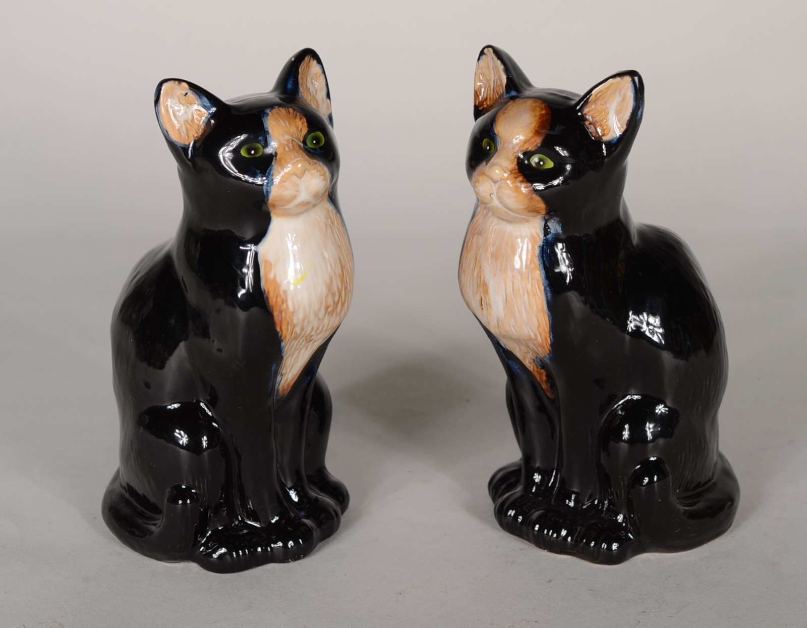 Duas esculturas de porcelana policromada representando gatos sentados. - foto 1 de 6