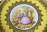 Par de medalhões de porcelana "Dom Pedro" decor... - Par de medalhões de porcelana "Dom Pedro" decorados com cenas românticas em policromia sobre fundo amarelo e guirlandas douradas.