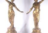 Par de grandes esculturas/luminárias de metal d... - Par de grandes esculturas/luminárias de metal dourado, representando figuras femininas segurando tocheiros, mangas de vidro fosco. Bases de made...