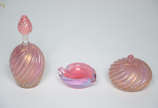 Três peças de murano na cor rosa, sendo dois pe... - Três peças de murano na cor rosa, sendo dois perfumeiros sem tampa com pó de ouro (um com bocal quebrado) e uma folha porta anéis. Alturas de 5 ...