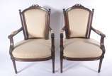 Par de cadeiras de madeira nobre, assentos e en... - Par de cadeiras de madeira nobre, assentos e encostos forrados em tecido bege com tacheados, detalhes entalhados.