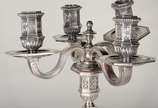 Christofle (1830),  - Candelabro de metal prateado para quatro velas, base feitio oitavado, trabalhado com guirlandas e figuras estilizadas em relevo. Com amassados.