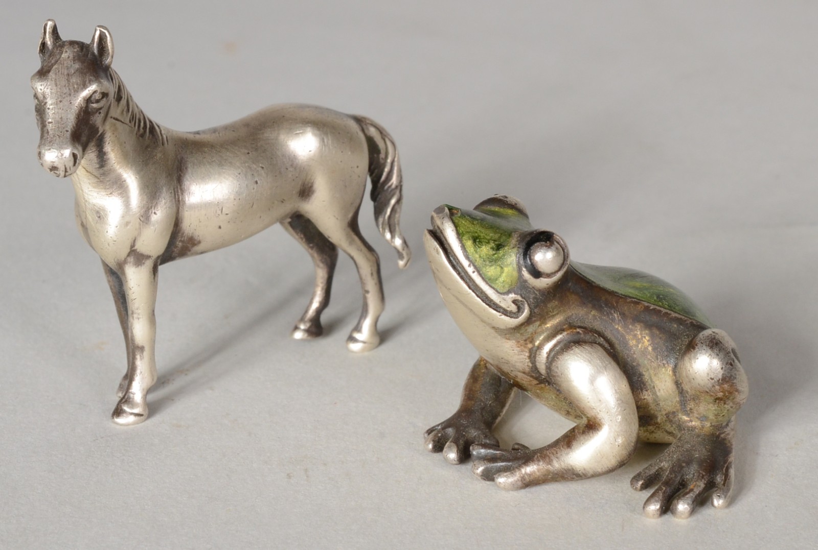 Duas pequenas esculturas de prata, sendo: cavalo e sapo com esmalte... - foto 1 de 9
