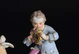 Meissen (1708),  - Duas esculturas de porcelana alemã, sendo uma representando anjo na fonte e outro representando menino segurando guirlanda, marcadas na base.