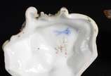 Meissen (1708),  - Duas esculturas de porcelana alemã, sendo uma representando anjo na fonte e outro representando menino segurando guirlanda, marcadas na base.