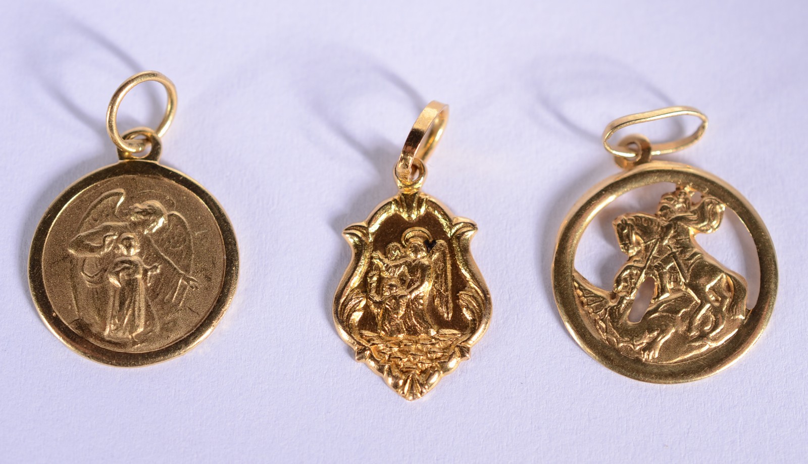 Três pendentes de ouro 18 k., contraste 750 mls, sendo: São Jorge... - foto 1 de 8