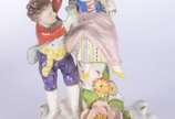Par de candelabros de porcelana alemã para 4 ve... - Par de candelabros de porcelana alemã para 4 velas cada, decorados com figuras infantis camponeses e flores em relevo policromado. Marcados na b...