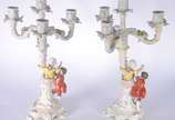 Par de candelabros de porcelana alemã para 4 ve... - Par de candelabros de porcelana alemã para 4 velas cada, decorados com figuras infantis camponeses e flores em relevo policromado. Marcados na b...