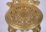 Cadeira de metal dourado trabalhado em relevo, ... - Cadeira de metal dourado trabalhado em relevo, encosto com medalhão decorado com figura de lenhador, assento com detalhes vazados.