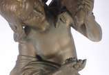 Estatueta de metal patinado representando figur... - Estatueta de metal patinado representando figura feminina com pássaro, acompanha coluna com tampo de vidro (metal com oxidação e desgastes).
