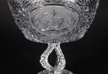 Duas fruteiras de cristal lapidado, sendo uma b... - Duas fruteiras de cristal lapidado, sendo uma baixa no feitio quadrangular e a outra de pé alto decorada com figuras de cisnes.