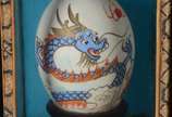 Par de "ovos" orientais com pinturas em policro... - Par de "ovos" orientais com pinturas em policromia representando "dragão" e "gueixa". Estojos forrados com tecido e vidro.