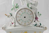 Relógio decorativo de mesa de porcelana Rosenth... - Relógio decorativo de mesa de porcelana Rosenthal  encimado por figura feminina e criança com corneta  ( funcionamento a pilha e faltando os pon...
