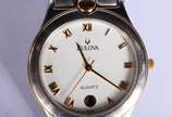 Bulova (1875),  - Relógio de pulso com caixa, pulseira, números e ponteiros em aço com dourado. No estojo, funcionando.