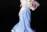 Estatueta de porcelana representando dama com c... - Estatueta de porcelana representando dama com cesto de flores.