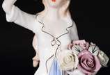 Estatueta de porcelana representando dama com c... - Estatueta de porcelana representando dama com cesto de flores.