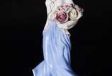 Estatueta de porcelana representando dama com c... - Estatueta de porcelana representando dama com cesto de flores.