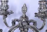 Par de candelabros de prata contrastada para 4 ... - Par de candelabros de prata contrastada para 4 velas cada, concheados e folhagens em relevo. Um deles quebrado. Peso da prata: 3040 g.  (Por mot...