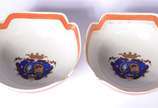 Par de bowls de porcelana com bordas recortadas... - Par de bowls de porcelana com bordas recortadas, tarjas na cor coral com guirlandas realçadas em dourado e brazões em policromia.