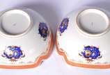 Par de bowls de porcelana com bordas recortadas... - Par de bowls de porcelana com bordas recortadas, tarjas na cor coral com guirlandas realçadas em dourado e brazões em policromia.