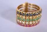 Anel de ouro 18 k., com 5 alianças com rubi, br... - Anel de ouro 18 k., com 5 alianças com rubi, brilhantes, esmeraldas e safiras azuis, aro 17. (Por motivos de segurança a peça não se encontra na...