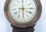 Ansonia Clock Company (1851-2006),  - Relógio de parede com caixa de madeira, mostrador com algarismos romanos e calendários externo com os dias do mes. Acompanha a chave. Desgastes. Máqui