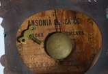 Ansonia Clock Company (1851-2006),  - Relógio de parede com caixa de madeira, mostrador com algarismos romanos e calendários externo com os dias do mes. Acompanha a chave. Desgastes. Máqui