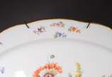 Meissen (1708),  - Travessa de porcelana alemã de Meissen, fundo branco decorado com ramos florais em policromia e borda recortada com friso dourado. Marca no verso. Séc