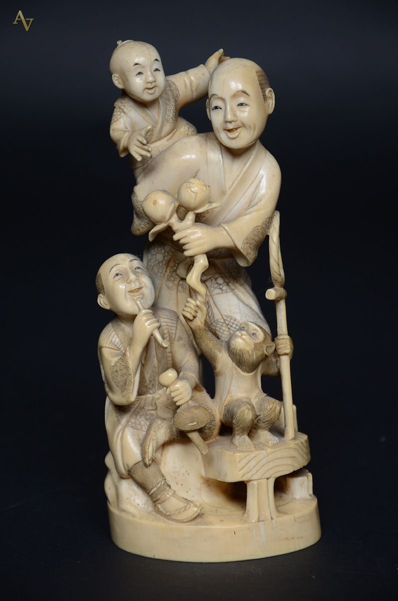 Escultura de marfim representando dois homens com criança e macaco... - foto 1 de 3