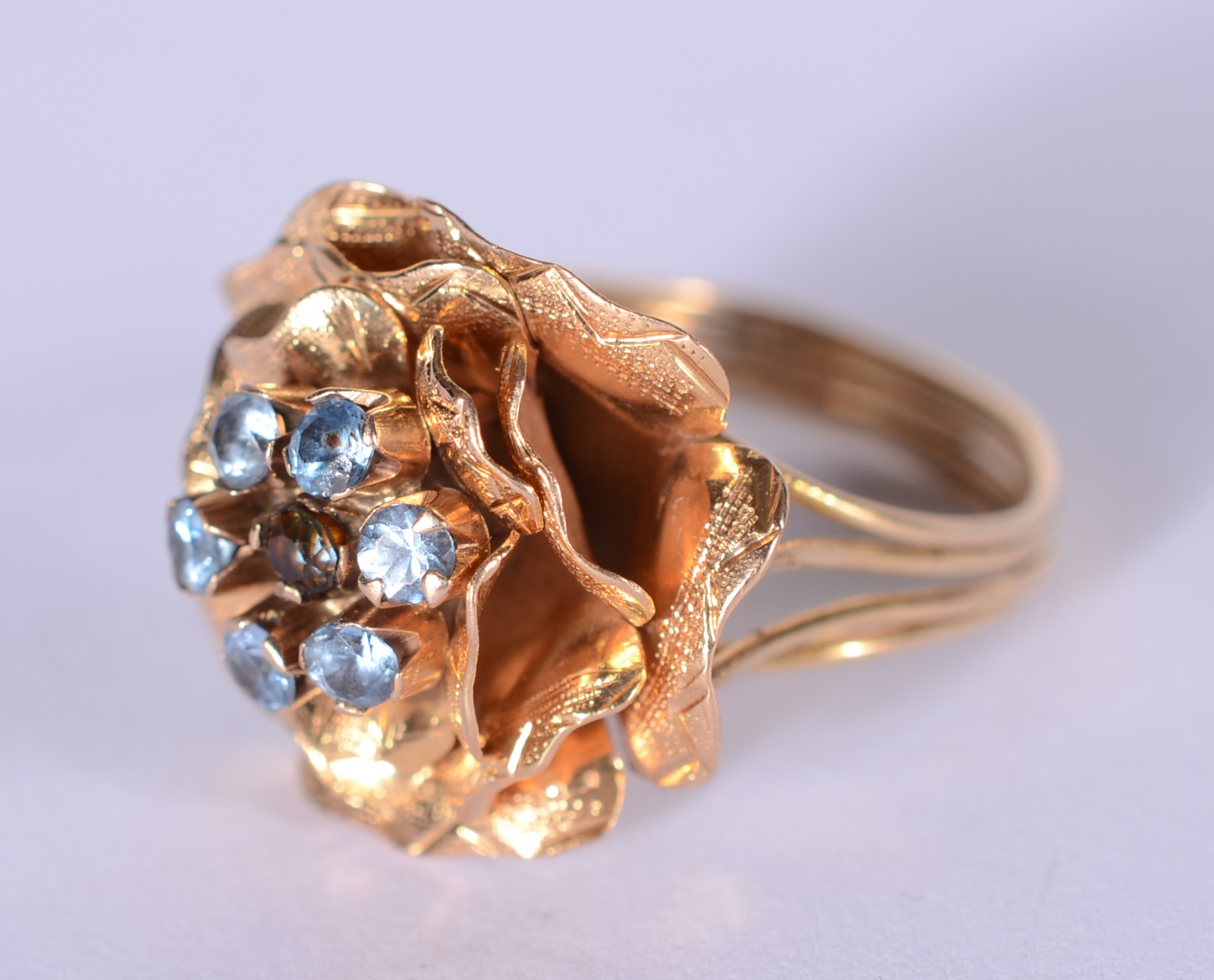 Anel de ouro 18 k., com flor cravejada de pedras azuis, aro 17. (Por... - foto 2 de 6