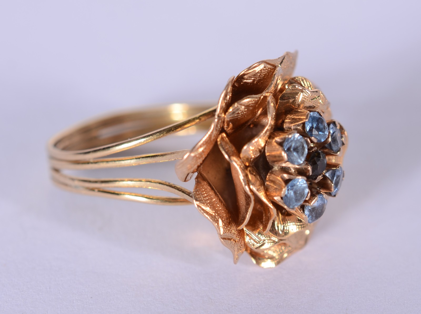 Anel de ouro 18 k., com flor cravejada de pedras azuis, aro 17. (Por... - foto 3 de 6