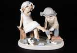 Lladró (1953),  - Estatueta de porcelana espanhola Lladró representando crianças com "sapatinhos" e gato. Partes coladas e faltando os dedinhos da menina. Marcas na bas