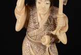 Netsuke de marfim oriental representando figura... - Netsuke de marfim oriental representando figura masculina com kimono e espada. Assinado.