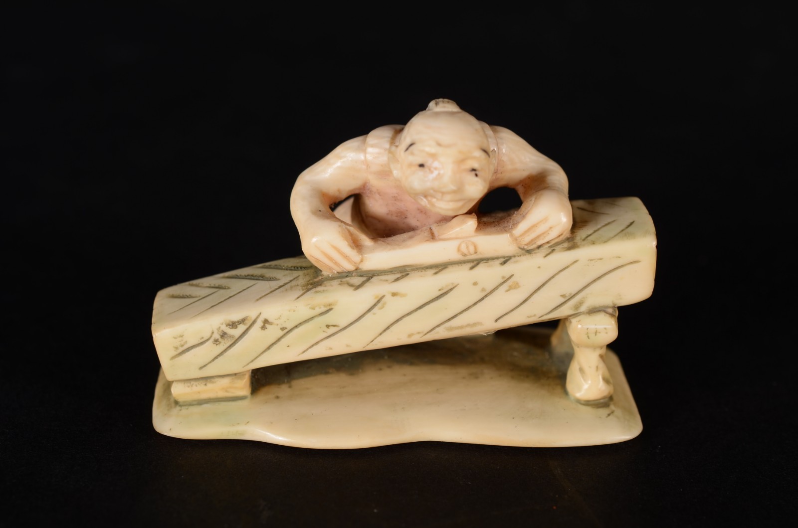 Netsuke de marfim oriental representando figura masculina em sua mesa... - foto 1 de 4