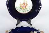 Duas peças de porcelana azul cobalto, sendo: fr... - Duas peças de porcelana azul cobalto, sendo: fruteira com alças realçadas em dourado e prato para bolo com cena romântica em policromia.