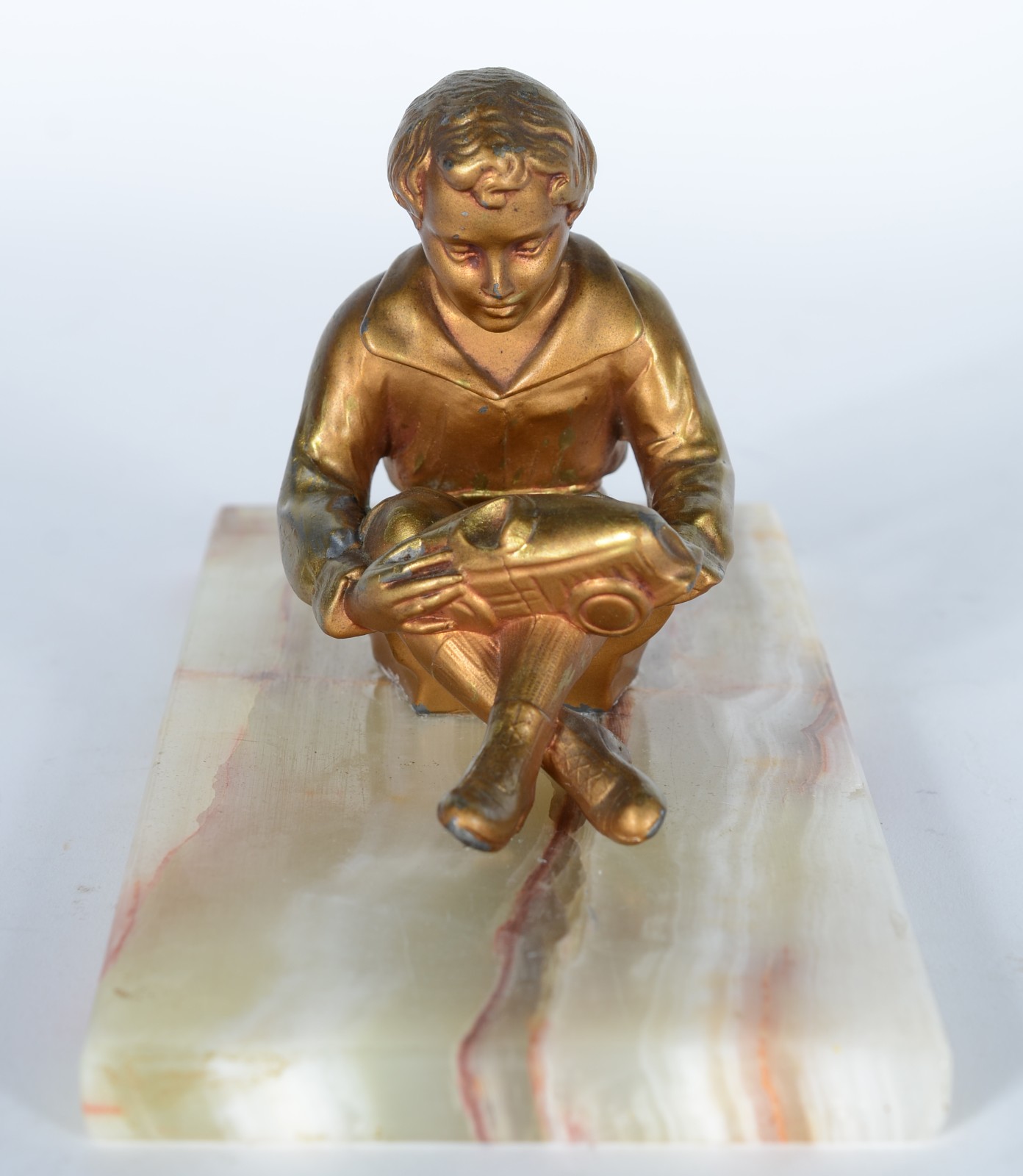 Escultura de metal dourado representando menino segurando carrinho... - foto 1 de 5